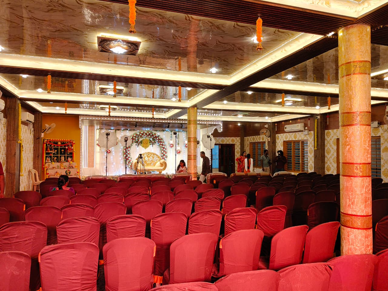 Convention hall arranged with maroon chair covers facing the wedding stage
